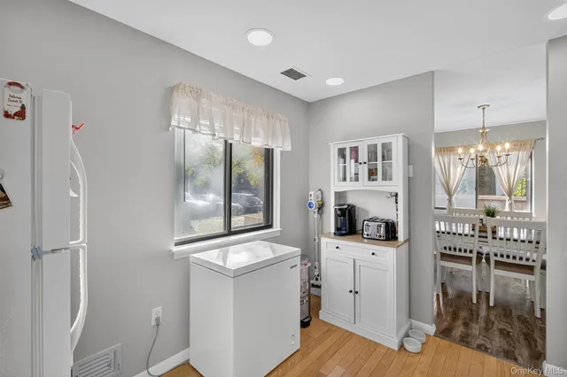 a view of a hallway with white cabinets and wooden floor