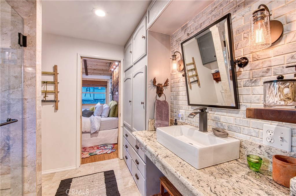 9287 Corral Road Forest Falls, CA 92339 - Photo 22 of 26 a en suite bathroom with a granite countertop sink and a mirror