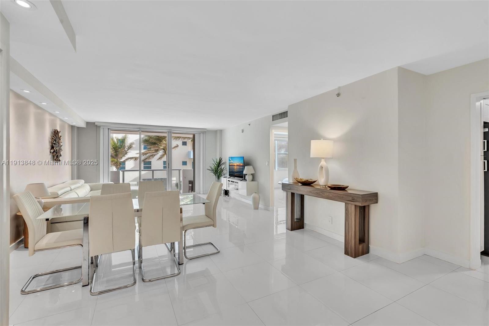 9195 Collins Avenue, Unit 303 Surfside, FL 33154 - Photo 14 of 44 a living room with furniture a dining table and chairs with kitchen view