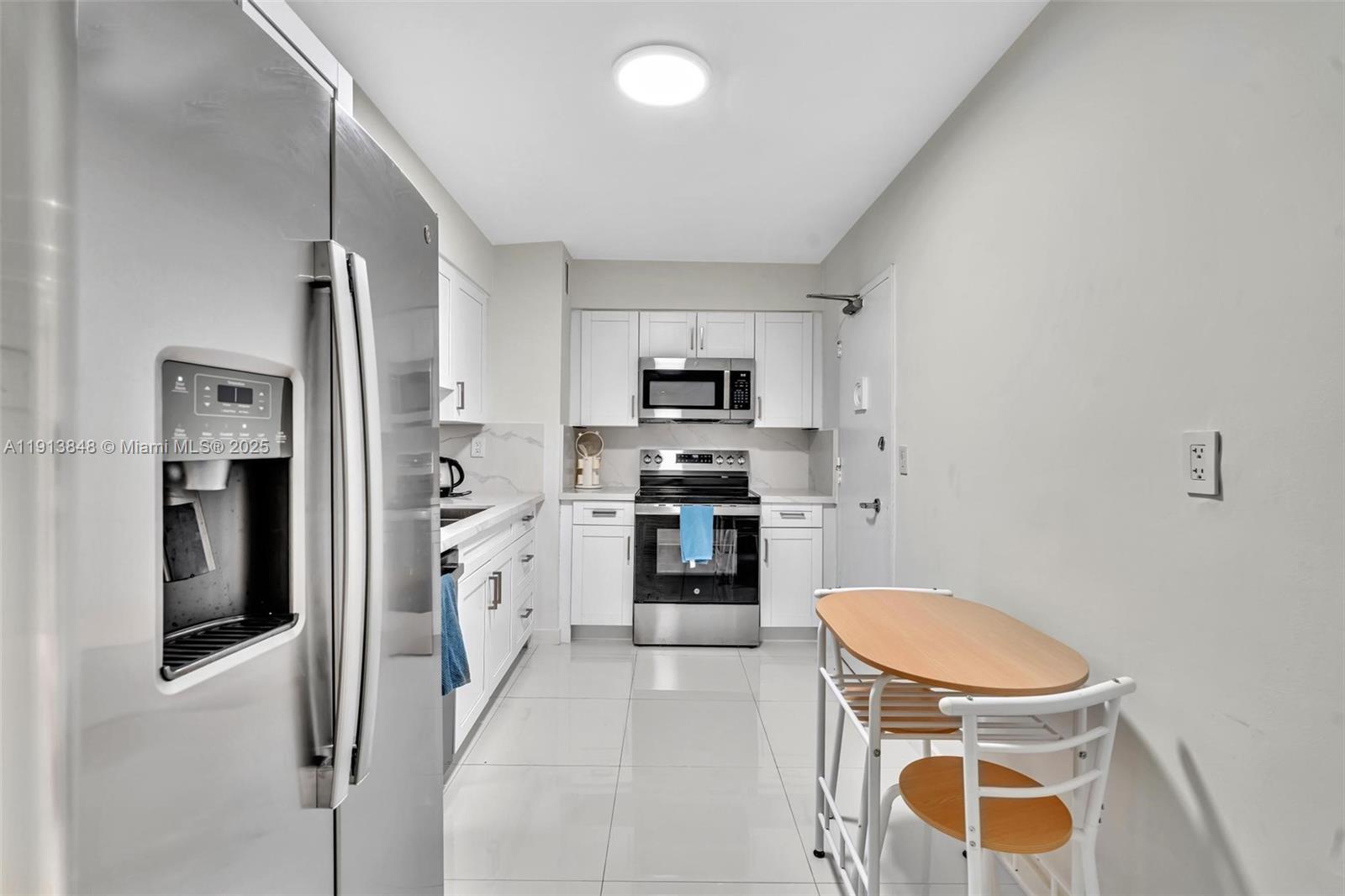9195 Collins Avenue, Unit 303 Surfside, FL 33154 - Photo 21 of 44 a kitchen with a refrigerator a stove top oven and a sink