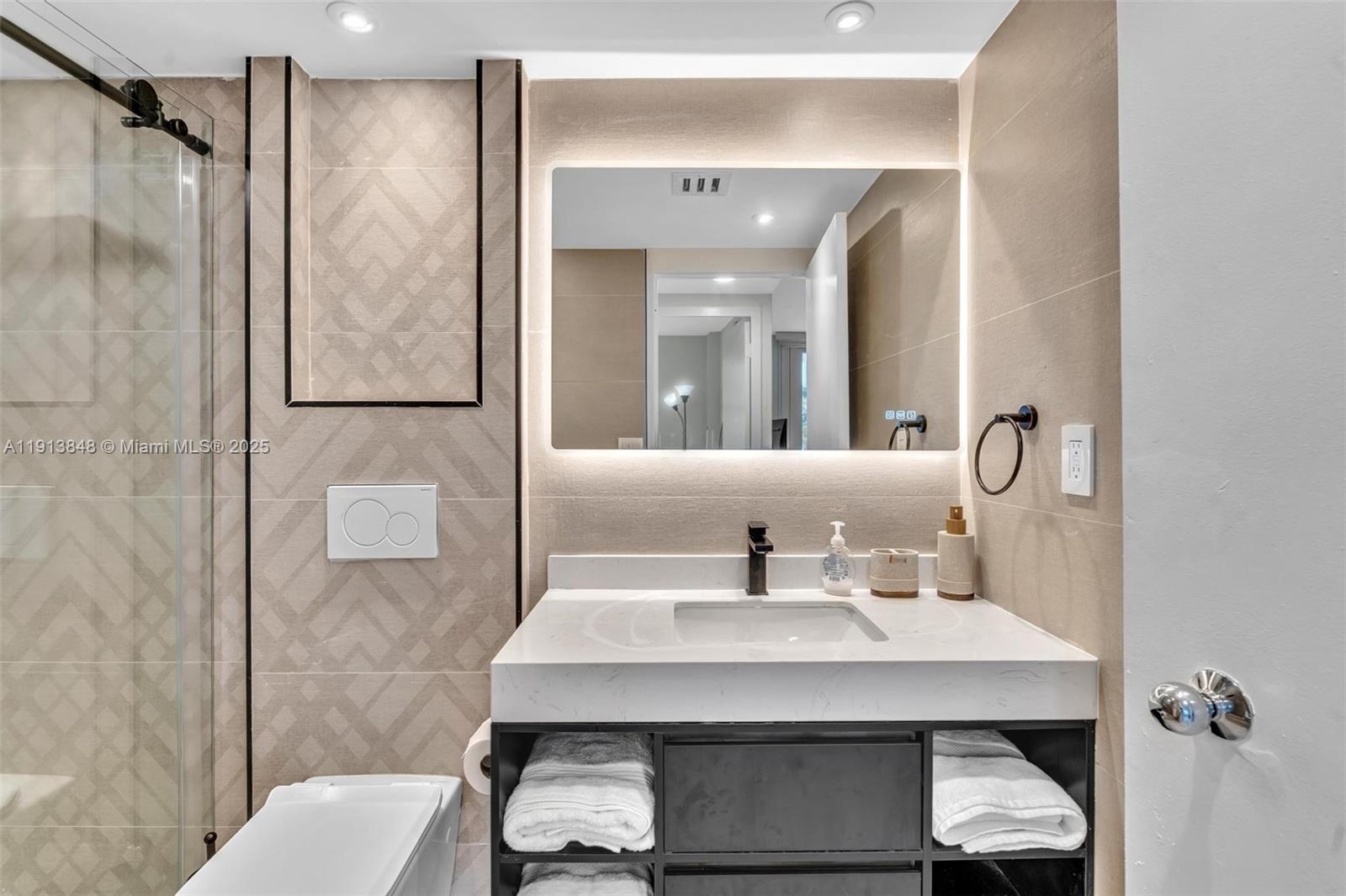 9195 Collins Avenue, Unit 303 Surfside, FL 33154 - Photo 30 of 44 a bathroom with a sink and a mirror