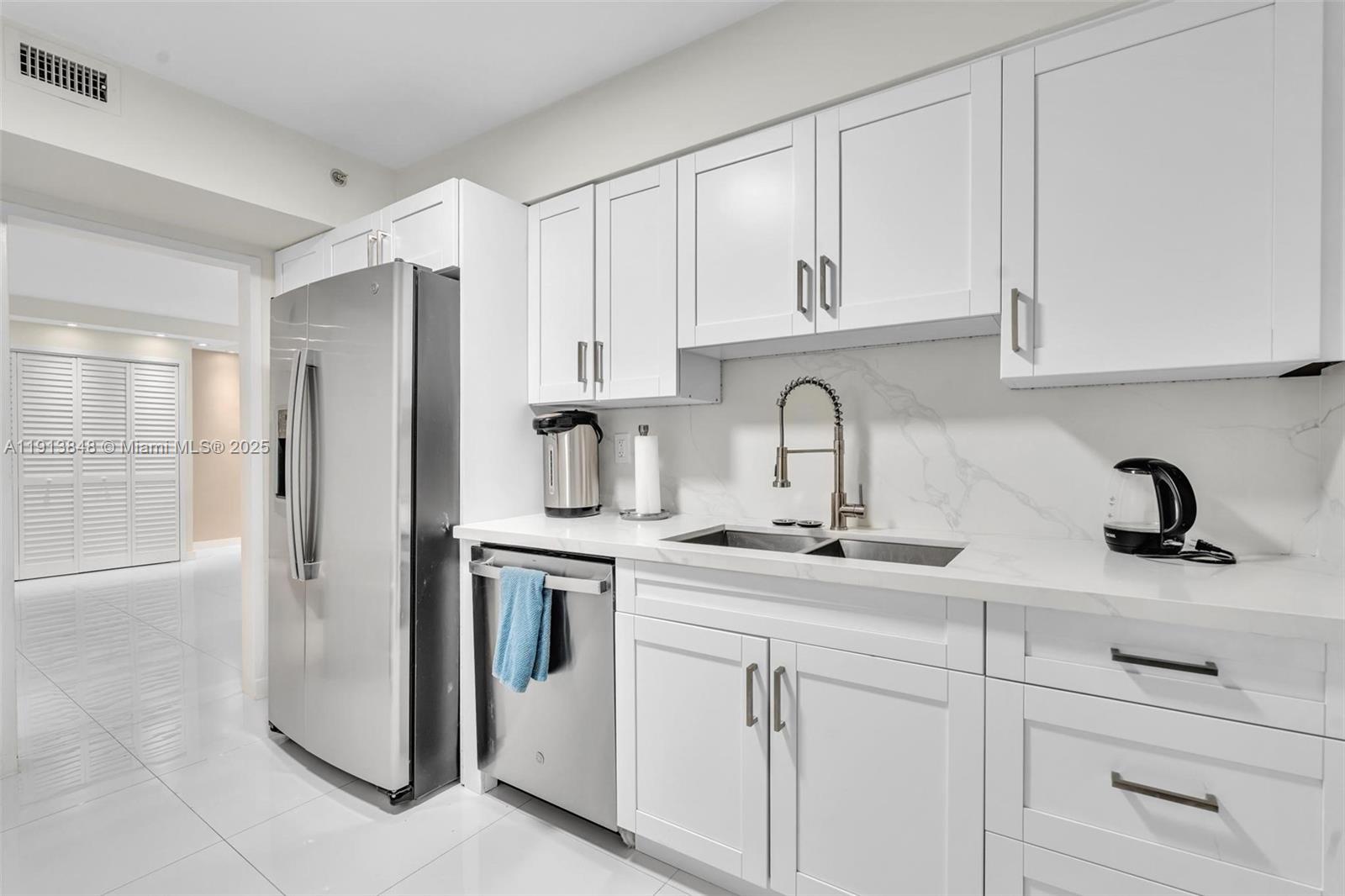 9195 Collins Avenue, Unit 303 Surfside, FL 33154 - Photo 3 of 44 a kitchen with white cabinets and sink