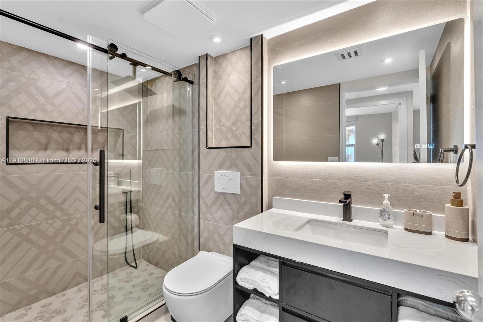 9195 Collins Avenue, Unit 303 Surfside, FL 33154 - Photo 4 of 44 a bathroom with a sink toilet a mirror and shower