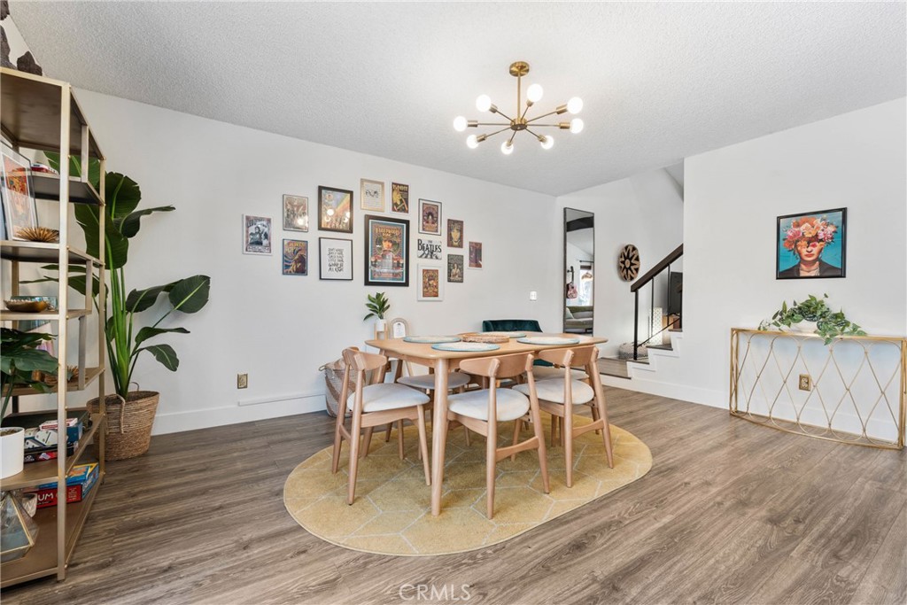 6134 Arroyo Road, Unit 3 Palm Springs, CA 92264 - Photo 7 of 35 a dining room with wooden floor a chandelier a wooden table and chairs