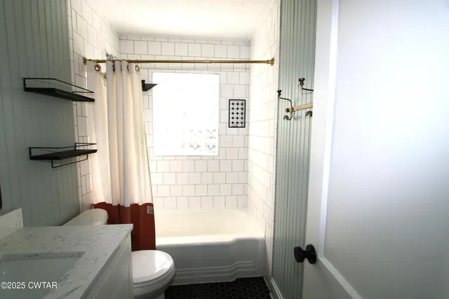 a bathroom with a granite countertop bathtub shower sink vanity and toilet