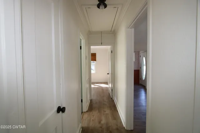 a view of a hallway with wooden floor and a bathroom