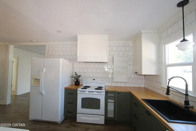 a kitchen with a refrigerator sink and white cabinets