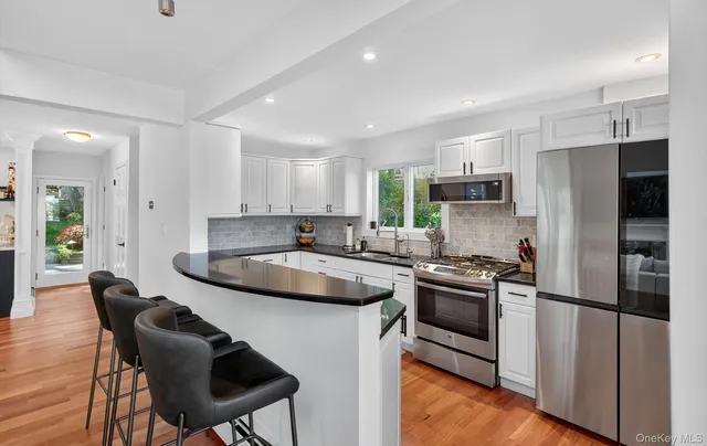 a kitchen with stainless steel appliances a stove a sink a microwave a refrigerator and cabinets