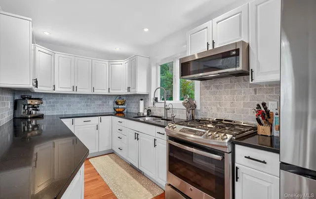 a kitchen with stainless steel appliances a sink a stove a microwave and cabinets