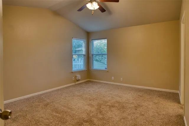an empty room with a chandelier fan and windows