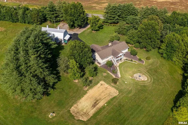 an aerial view of residential house with outdoor space and trees all around