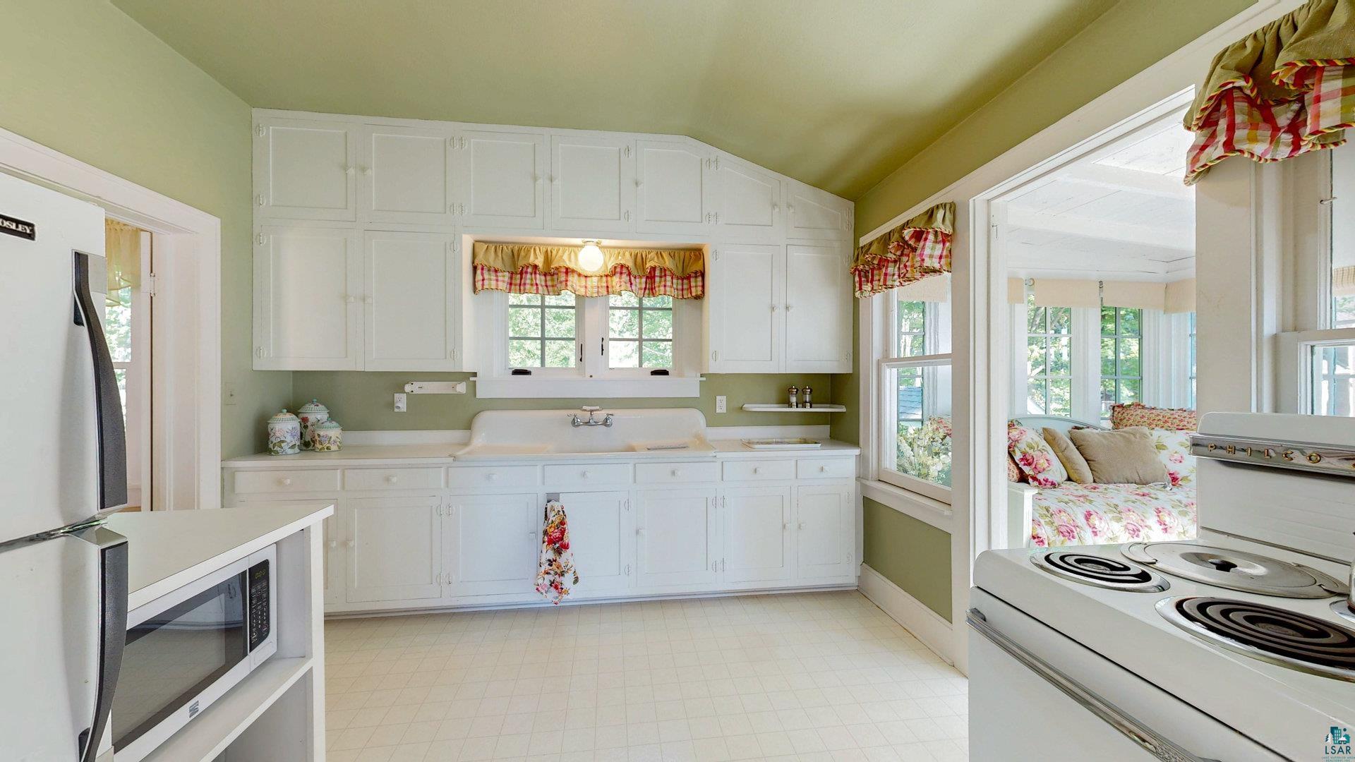 N1211 East Side Road Birchwood, WI 54817 - Photo 63 of 70 Kitchen featuring light flooring, white appliances, lofted ceiling, white cabinetry, and light countertops
