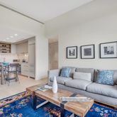 a living room with furniture a rug and a dining table with wooden floor