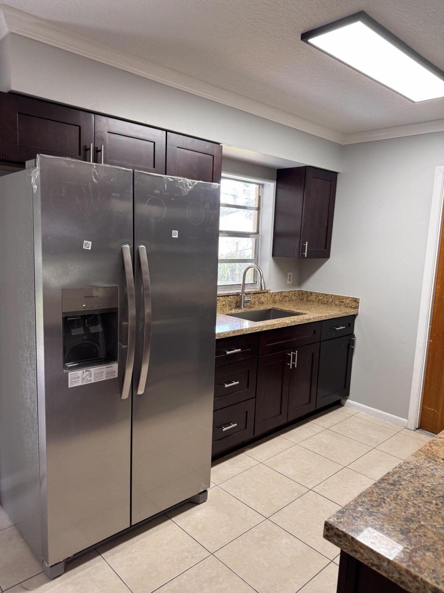 7408 Donlon Road Fort Pierce, FL 34951 - Photo 3 of 17 a kitchen with a refrigerator and cabinets