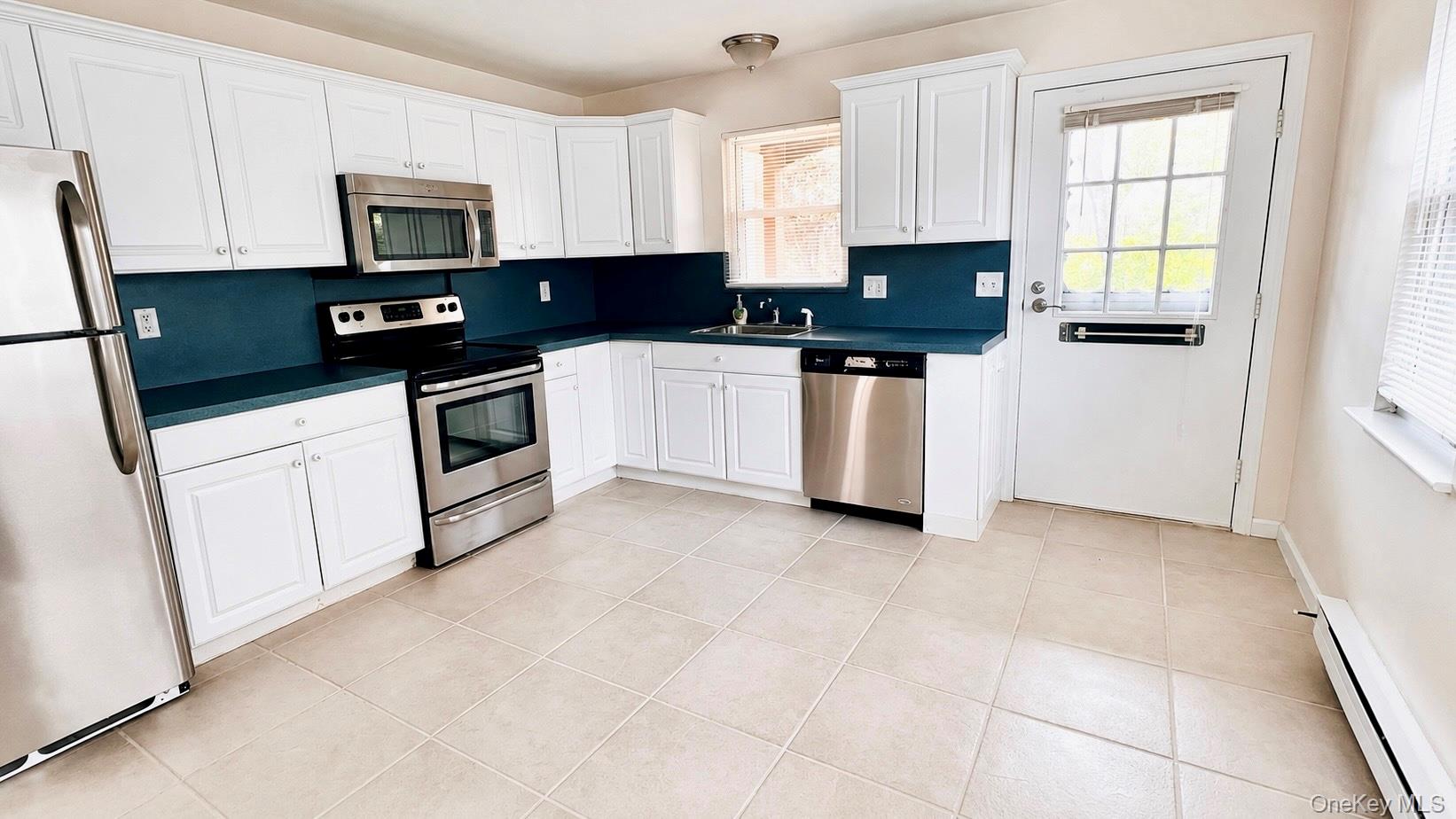 257 Edinburgh Drive Ridge, NY 11961 - Photo 6 of 10 a kitchen with granite countertop white cabinets and black appliances