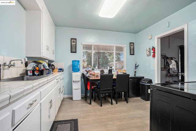 a kitchen with stainless steel appliances a sink a stove a refrigerator cabinets and chairs