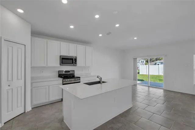 a kitchen with granite countertop a sink a stove cabinets and counter space