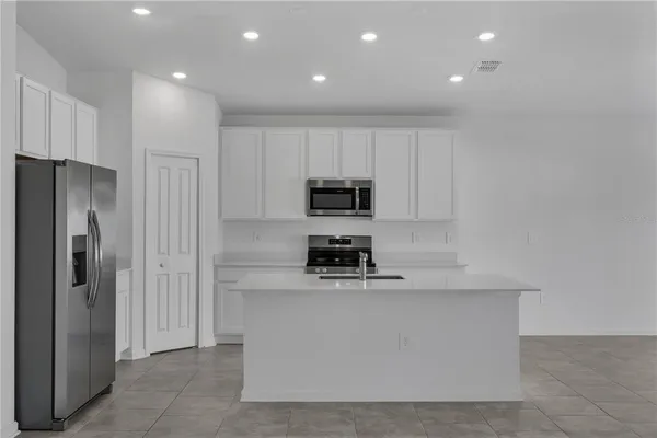 a kitchen with stainless steel appliances granite countertop a refrigerator a stove and a sink