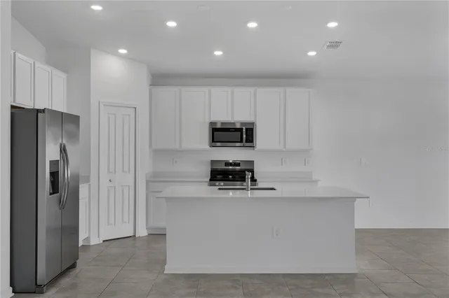 a kitchen with stainless steel appliances granite countertop a refrigerator a stove and a sink