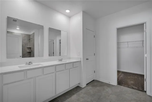 a spacious bathroom with a double vanity sink a mirror and a shower