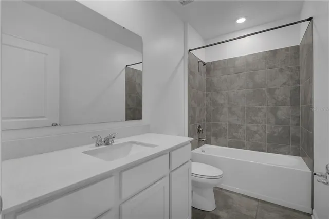 a bathroom with a bathtub shower sink vanity mirror and toilet