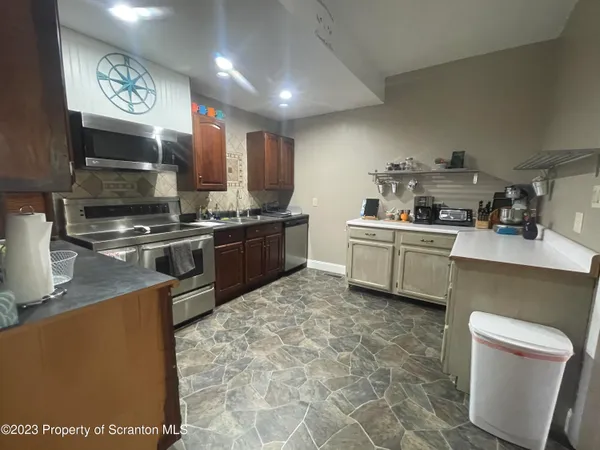 a kitchen with stainless steel appliances granite countertop a sink a stove top oven a chimney a counter top space and cabinets