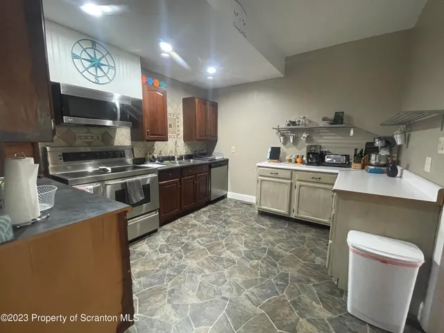 a kitchen with stainless steel appliances granite countertop a sink a stove top oven a chimney a counter top space and cabinets