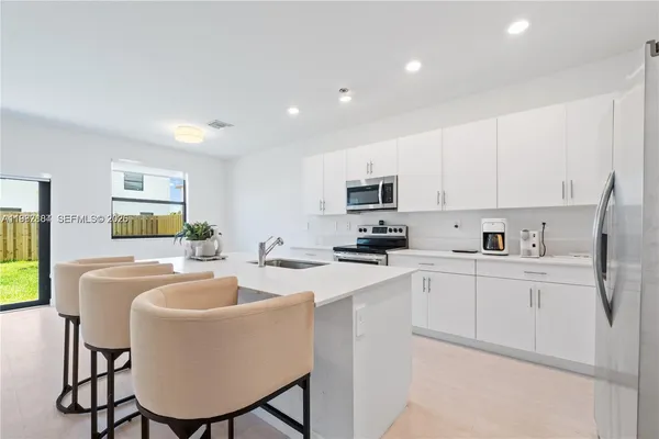 a kitchen with stainless steel appliances a white table chairs and a refrigerator