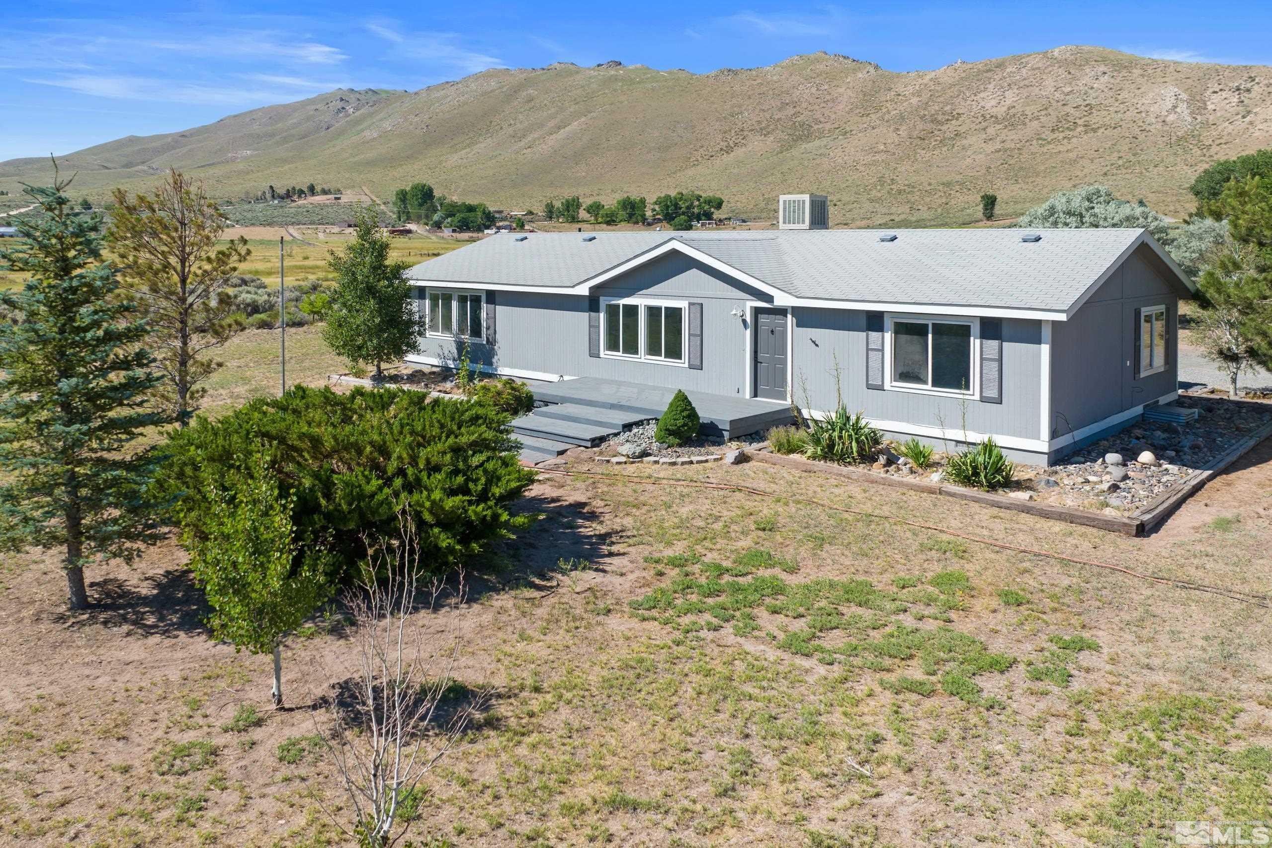 a front view of a house with a yard and mountain view in back
