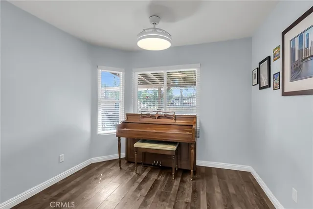 a view of a room with wooden floor a ceiling fan and windows