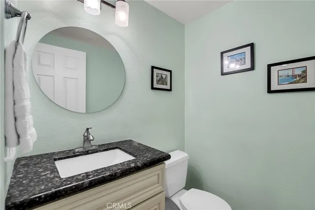 a bathroom with a granite countertop toilet a sink and a mirror