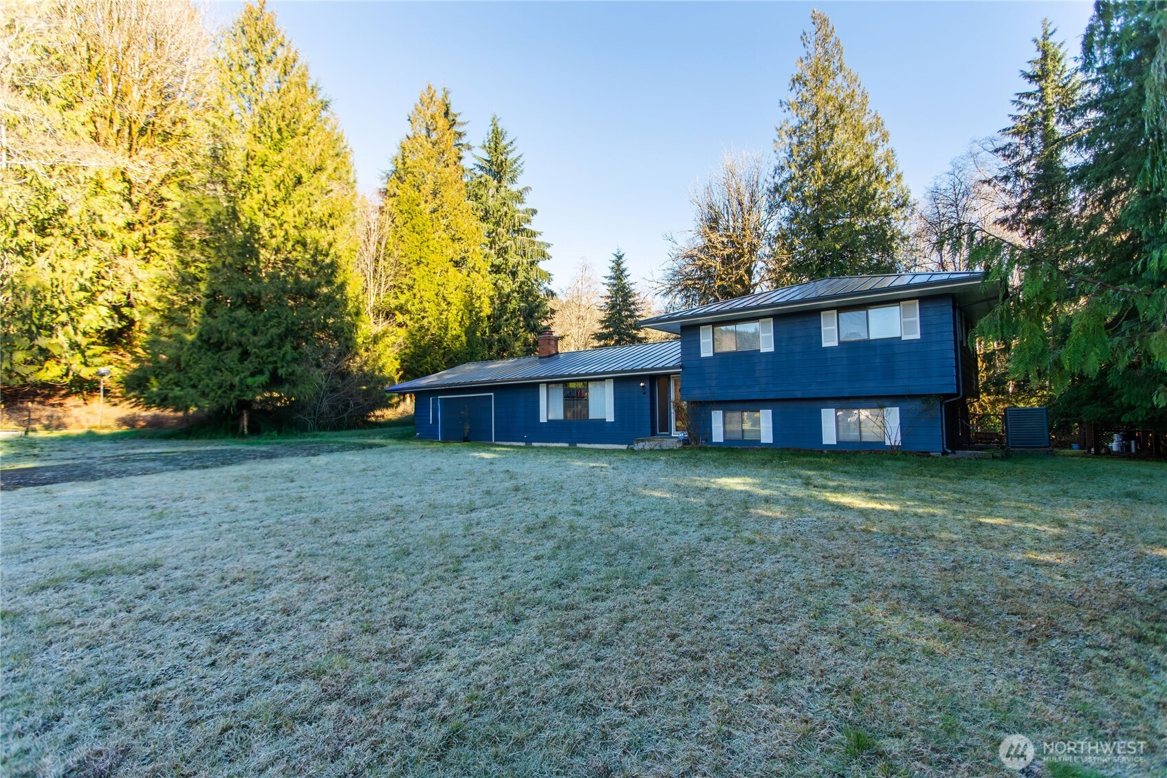 a view of a house with a yard and large trees