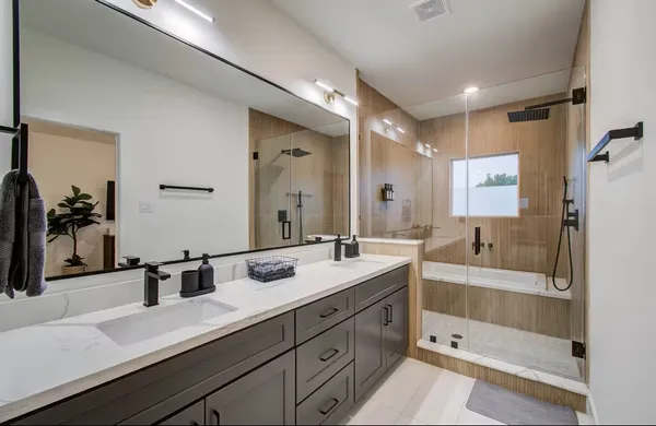a bathroom with a sink double vanity granite tub shower and a mirror