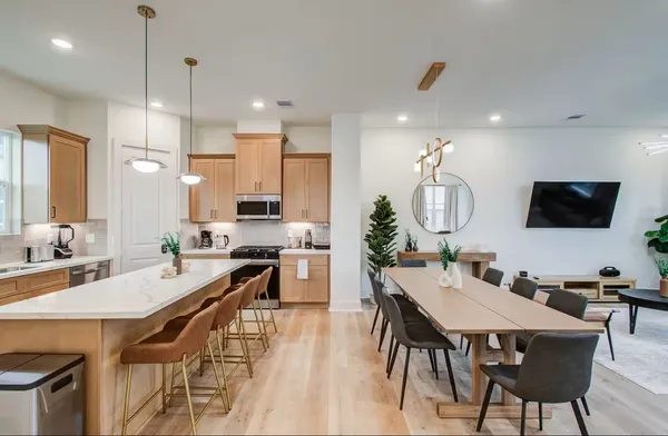 a view of a dining room with furniture a kitchen and chandelier