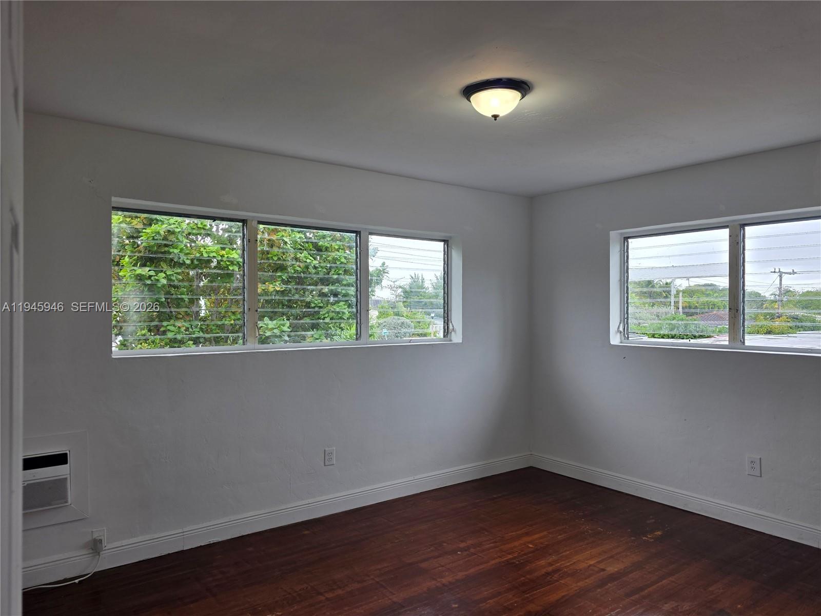 824 82nd Street, Unit 4 Miami Beach, FL 33141 - Photo 12 of 13 a view of an empty room with wooden floor and a window