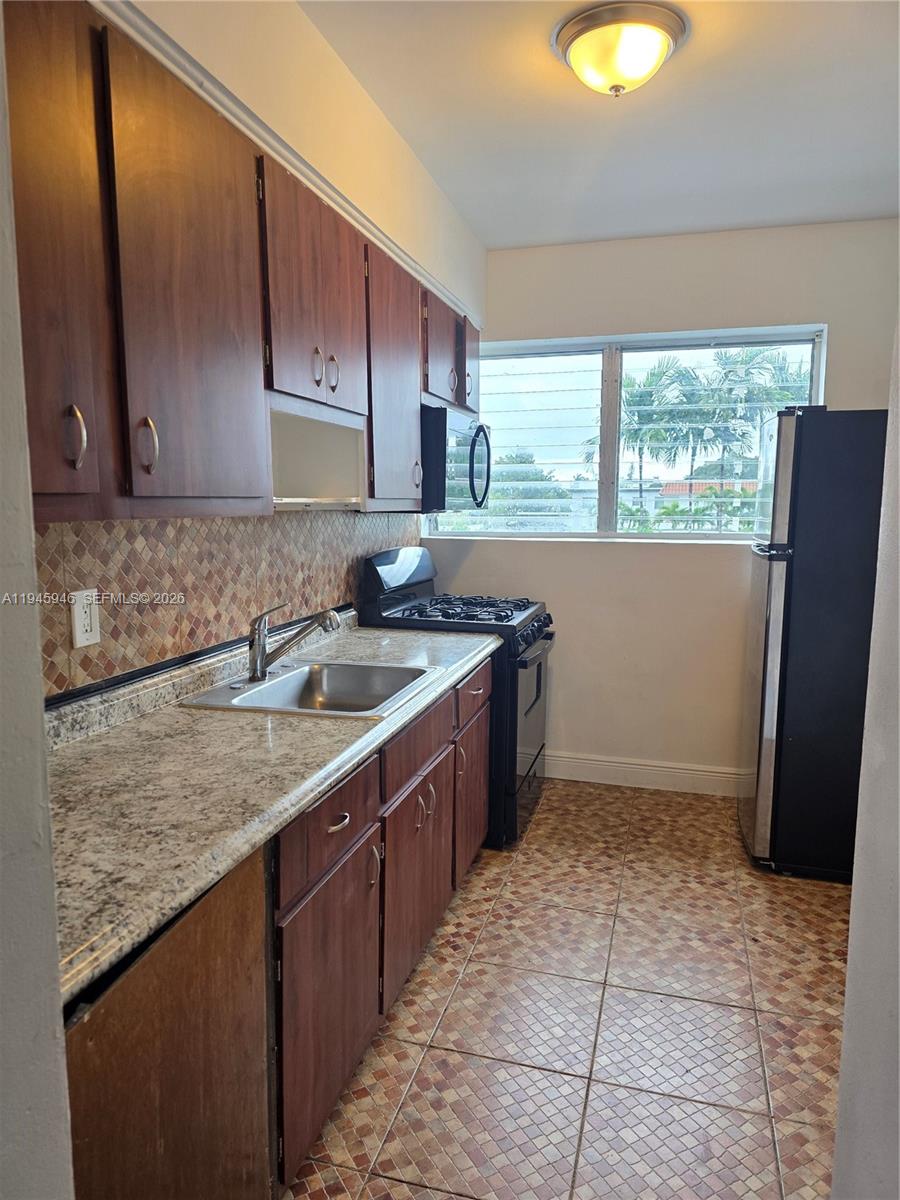 824 82nd Street, Unit 4 Miami Beach, FL 33141 - Photo 7 of 13 a kitchen with a sink a stove cabinets and a wooden floor