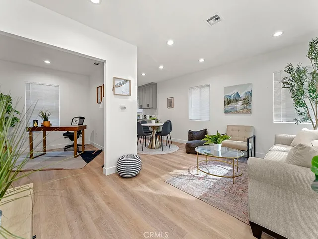 a living room with furniture and a dining table with wooden floor
