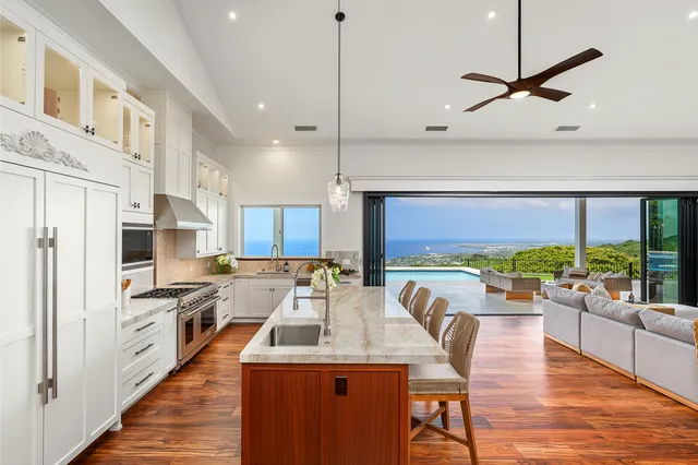 a kitchen with stainless steel appliances granite countertop a refrigerator a sink a stove and white cabinets with wooden floor