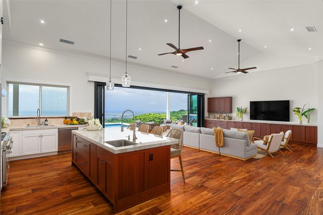 a living room with stainless steel appliances kitchen island granite countertop a sink dishwasher a flat tv screen and a dining table with wooden floor