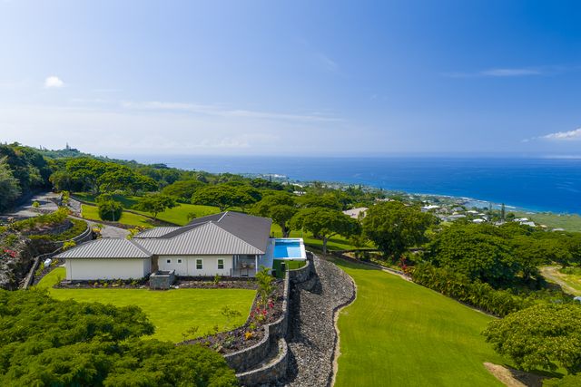an aerial view of a house having swimming pool a yard and lake view
