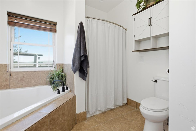 1634 West Arimo Road Arimo, ID 83214 - Photo 15 of 89 Bathroom featuring a built-in tub with tile surround, a window with wood blinds, and a white toilet