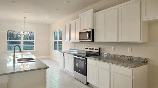 a kitchen with stainless steel appliances granite countertop a stove a sink and a microwave