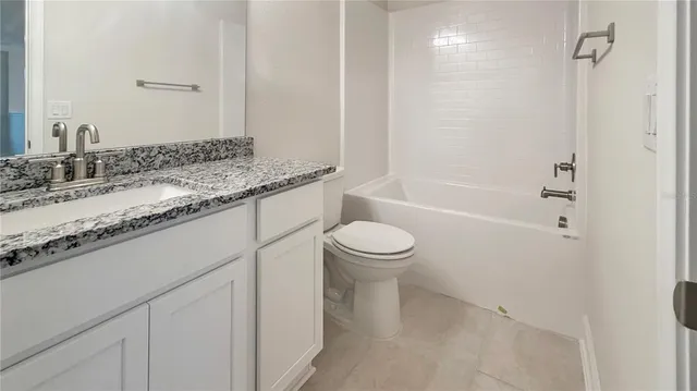 a bathroom with a granite countertop sink a toilet and bathtub