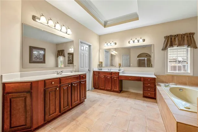 a spacious bathroom with a tub a sink double vanity and a mirror