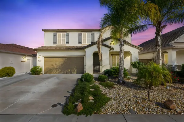 a front view of a house with a yard and potted plants