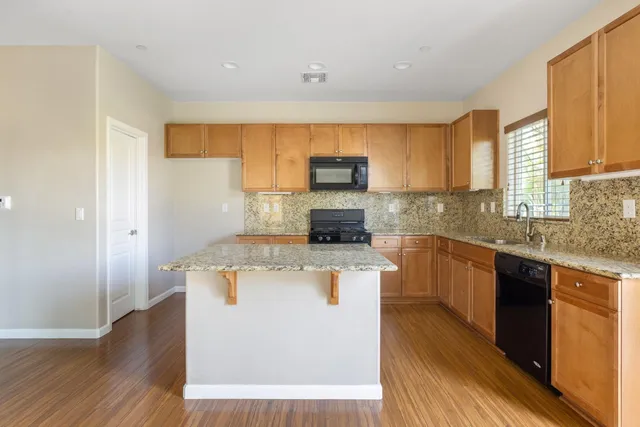 a kitchen with a stove a sink a microwave a refrigerator and cabinets