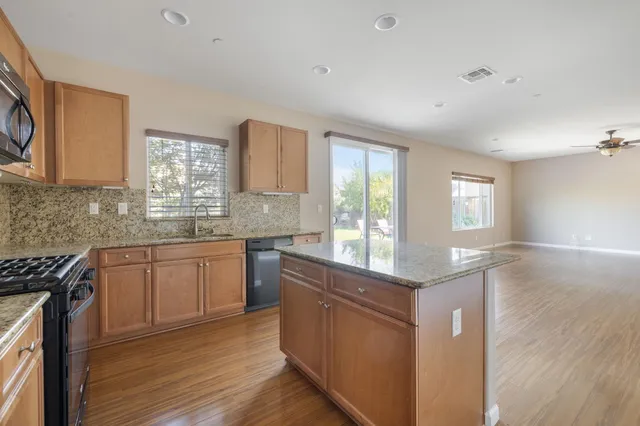 a kitchen with granite countertop cabinets stainless steel appliances a sink and a window