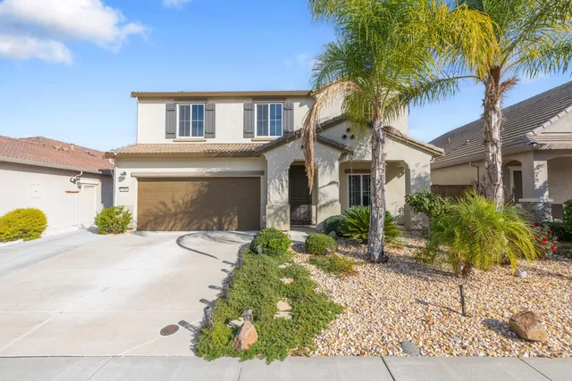 a front view of a house with a yard and potted plants