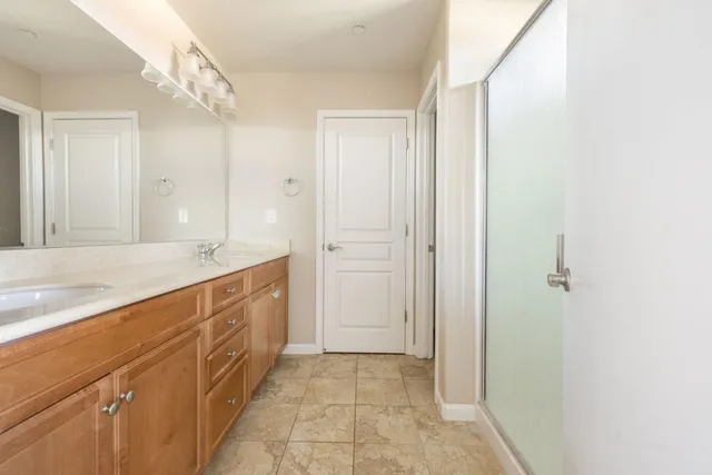 a spacious bathroom with a double vanity sink a mirror and a shower