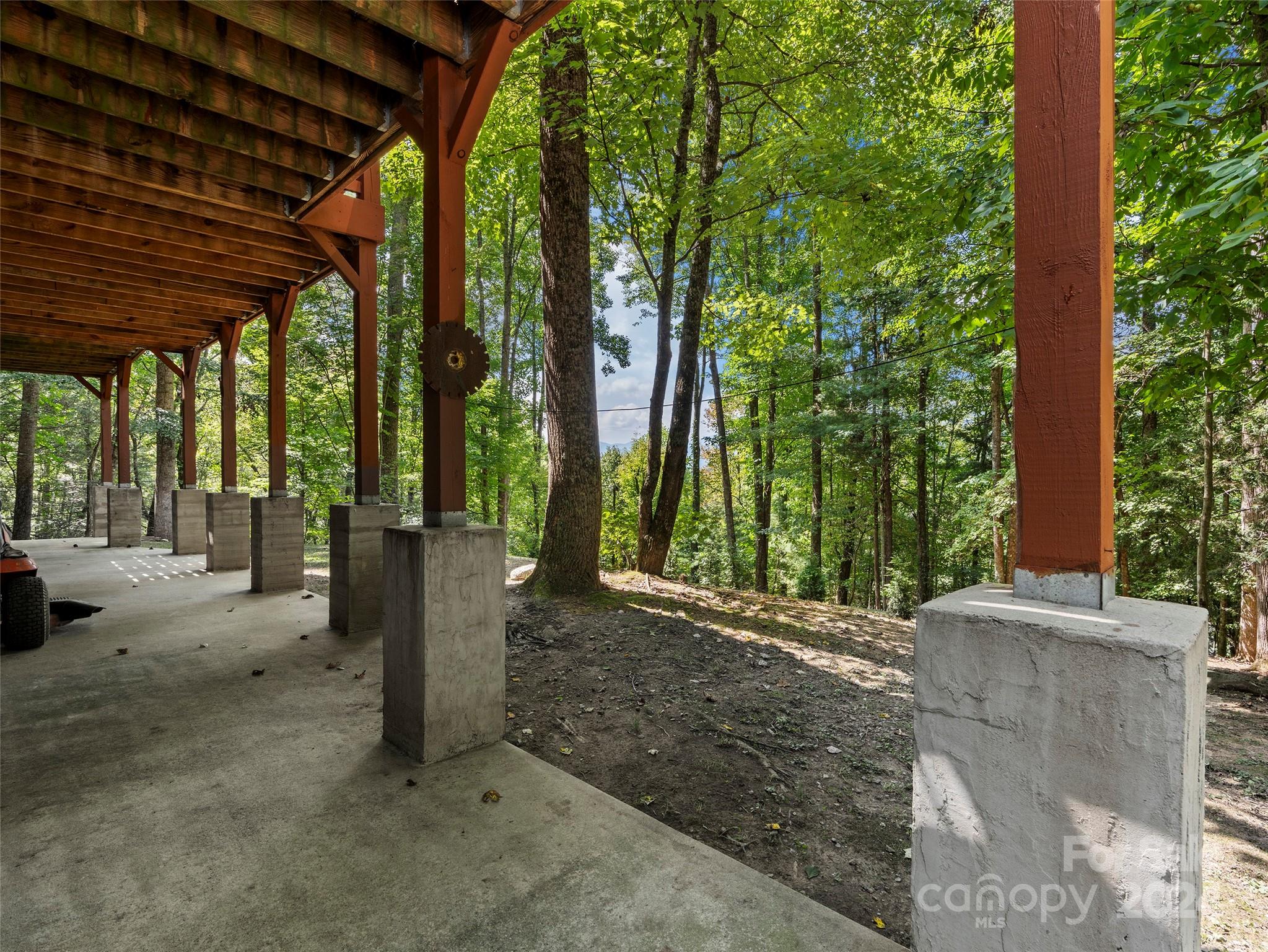 25 Dawn Valley Road Waynesville, NC 28785 - Photo 33 of 46 a view of a patio with a table and chairs under an umbrella with a large tree